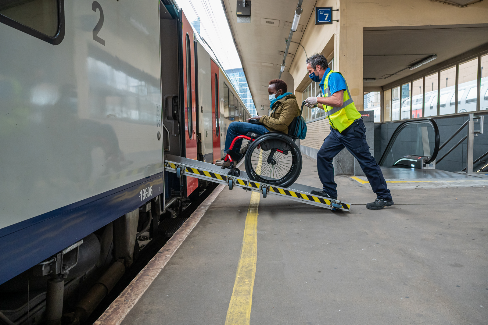 personne en chaise montant dans un train via la rampe
