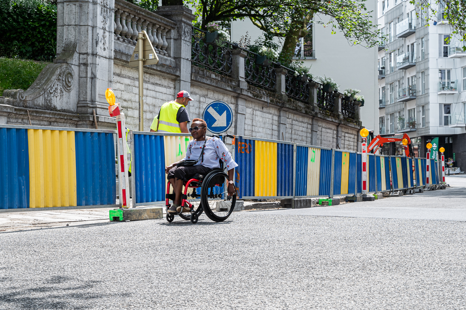 Personne en chaise roulante contournant des obstacles de chantier sur un trottoir, illustrant les difficultés d’accessibilité pour les piétons
