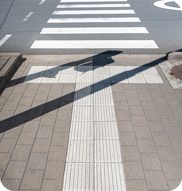 Passage piéton équipé de dalles podotactiles et de bandes de guidage au sol pour faciliter les déplacements des personnes malvoyantes.